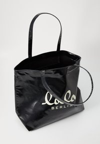 Borsa tote nera lucida con due manici e logo "lolo BERLIN" in bianco. Forma rettangolare, interno spazioso, texture liscia.