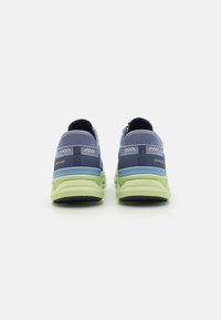 Baskets de sport slip-on bleu et vert avec un dessus en maillage texturé, un col rembourré et des semelles rembourrées avec des accents contrastants sur le talon.