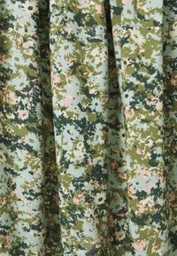 Stoff mit einem Blumen- und Camouflage-Muster in Grüntönen, Hellblau und zartem Rosa. Die Textur wirkt glatt und gewebt.