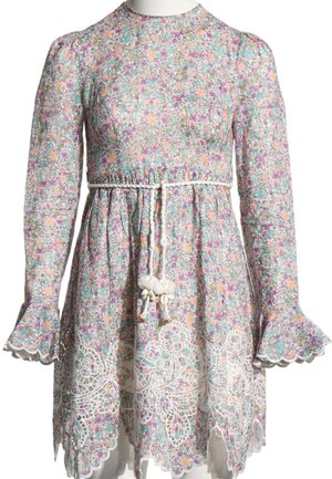 Robe fleurie à manches longues avec de petites fleurs roses, violettes et vertes, ourlet festonné en dentelle et ceinture blanche tressée avec des pompons à la taille.