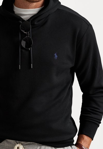 Sweatshirt preto com bolso frontal, capuz com cordão, logótipo azul bordado no peito, punhos e bainha canelados, tecido parece macio e texturado.