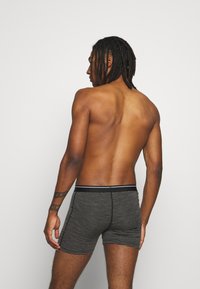 Svart og gråstripete boxershorts med svart midjebånd, tettsittende design som former seg etter kroppen, vist fra bakvinkel.