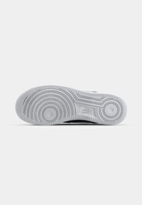 Nike potplat tenisica, bijela guma s kružnim uzorcima, izbočine za prianjanje, s diskretnim utisnutim logom. Ravni oblik dizajniran za stabilnost.