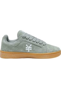 Grå semsket sneaker med avrundet tå, snøring og hvit logo på siden. Har en såle av gummigummi for godt grep.