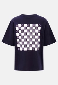 Ναυτικό μπλε T-shirt με λευκό καρό σχέδιο στην πίσω πλευρά, που εμφανίζει εναλλασσόμενα τετράγωνα και χαμογελαστά πρόσωπα.