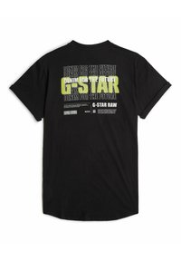 Camiseta negra con texto en blanco y neón en la parte posterior, que dice "DENIM PARA EL FUTURO" junto con detalles de logotipo y código de barras. Mangas cortas.