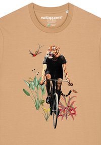 Beige T-shirt met een grafische print van een fietser in een zwart outfit en tijgerhoofd, omringd door planten en een kolibrie.