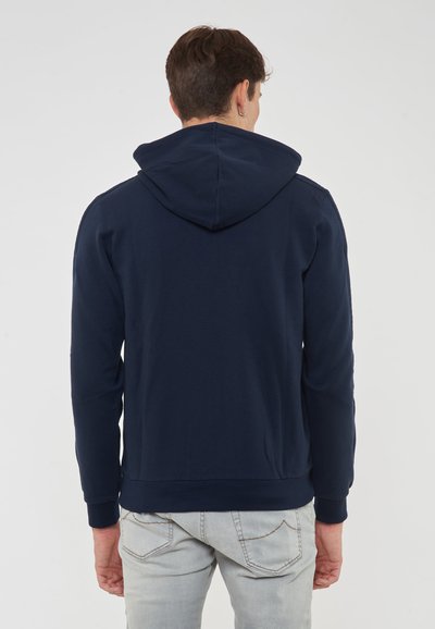 Marinblå huvtröja gjord av mjukt tyg, med en kenguruficka och ribbade ärmar. Texturerat tyg med minimala design detaljer.