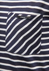 Námořnická a bílá pruhovaná látka se čtvercovou náprsní kapsou, na které je černá nálepka s nápisem "ONLY." Hladká textura, neformální design.