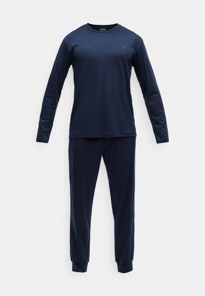 Donkerblauwe langetermijnsleeve shirt en bijpassende broek gemaakt van gladde stof; shirt heeft een ronde halslijn en een subtiel logo nabij de borst.