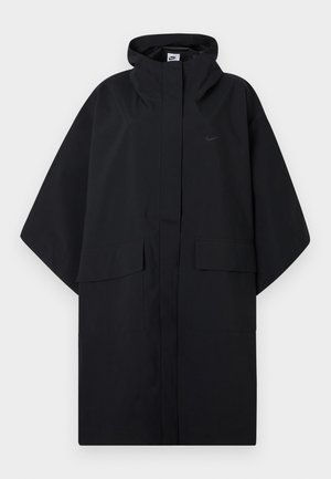 Poncho imperméable noir Nike avec capuche, fermeture velcro à l'avant, deux poches à rabat et manches larges et amples.