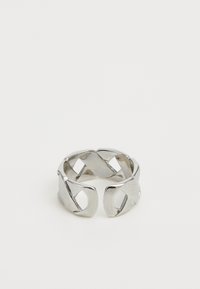 Sølvmetallring med et sammenkoblende design, flate, glatte overflater og utskårne detaljer, som viser en moderne geometrisk stil.