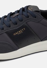 Granatowe sneakersy z teksturowanej skóry i gładkiego materiału syntetycznego, z tonowanymi sznurowadłami, złotymi akcentami logo i białą podeszwą.