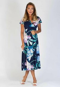 Kukallinen midi-mekko, jossa on tummansininen tausta ja suuria vaaleansinisiä ja purppuran värisiä kukkia. Lyhyet hihat, kietaisumalli ja virtaava kangas.