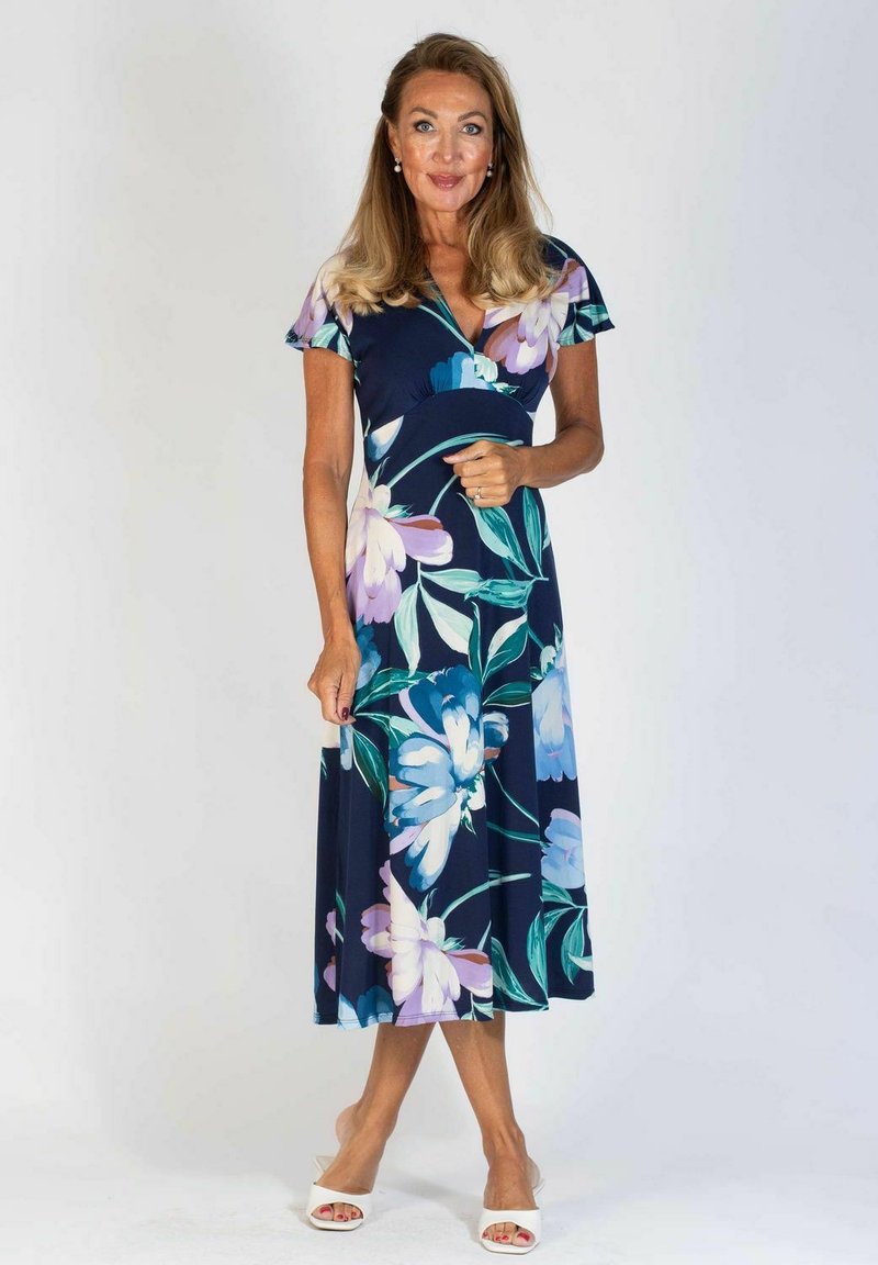 Kukallinen midi-mekko, jossa on tummansininen tausta ja suuria vaaleansinisiä ja purppuran värisiä kukkia. Lyhyet hihat, kietaisumalli ja virtaava kangas.