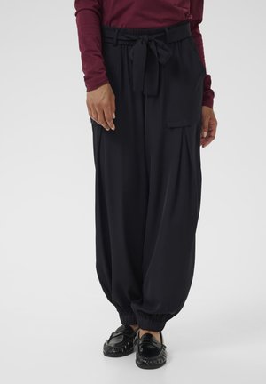 Pantaloni neri fluida con vita arricciata e dettaglio legato, caratterizzati da gambe larghe, tasche laterali e polsini elasticizzati.