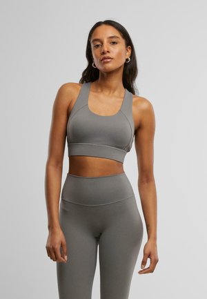 Grijze sportbh met een brede band en dikke straps, gecombineerd met hoge grijze legging die een gladde textuur en minimale naden heeft.