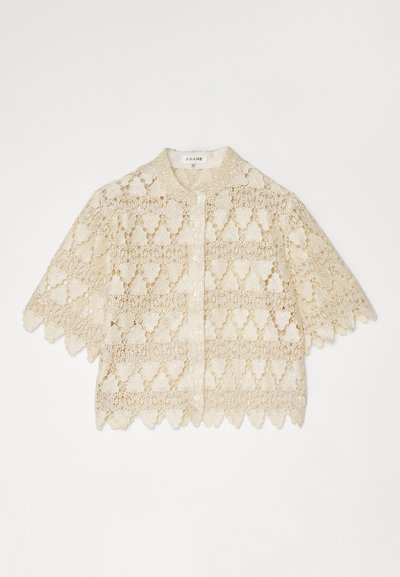 Cream-colored lace blouse with short sleeves, button-down front, floral patterns, scalloped edges, and a small collar.