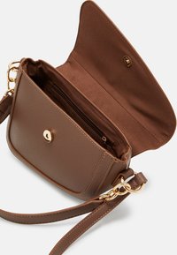 Sac en cuir marron à bandoulière avec une finition texturée, quincaillerie dorée et un seul compartiment zippé à l'intérieur. Design à rabat ouvert.