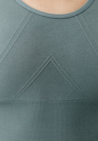 Svetle tyrkysový seamless top bez rukávů s texturovaným pletením, žebrovanými detaily a jemným trojúhelníkovým vzorem na prsou.