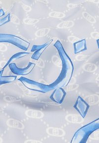 Bufanda de seda con una base blanca, que presenta formas geométricas azules y un patrón repetido de diseños interconectados. Textura suave y lisa.