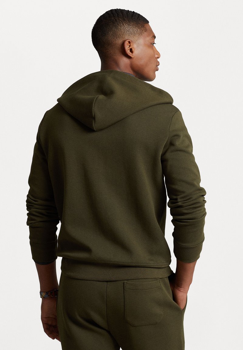 Bluza z kapturem w ciemnooliwkowym kolorze, o luźnym kroju, z ribbami na mankietach oraz kieszenią kangurką. Gładka faktura i minimalistyczny design.