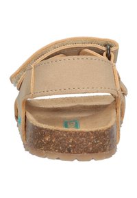 Beige sandalen met een getextureerde leren band en een kurken zool. Verstelbare achterkant met een metalen gesp. Vlakke, open teen ontwerp.