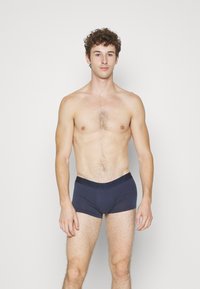 Boxer da uomo in cotone blu navy con una morbida cintura elastica che presenta il logo Calvin Klein, progettati per offrire comfort e una vestibilità aderente.