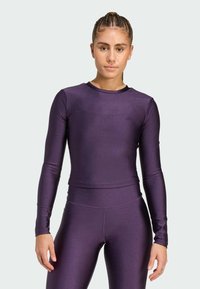 Purple long-sleeve athletic top in a fitted design, made of shiny stretch material. Features a rounded neckline and matching leggings.