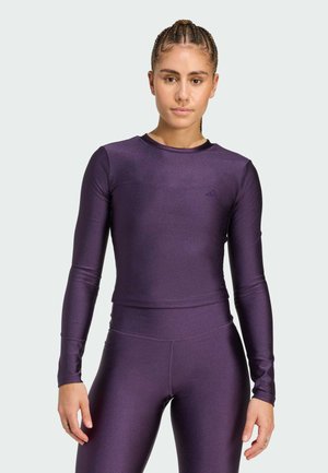 Maglietta atletica a maniche lunghe in viola, dal design aderente, realizzata in materiale elastico lucido. Presenta un collo rotondo e leggins coordinati.