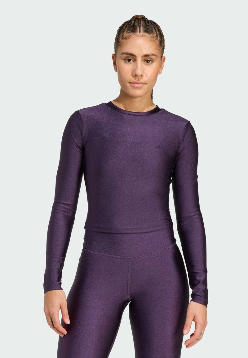 Purple long-sleeve athletic top in a fitted design, made of shiny stretch material. Features a rounded neckline and matching leggings.