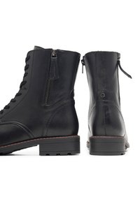 Černé kožené kotníkové boty s šněrováním v přední části, bočním zipem, kulatou špičkou, pevným podpatkem a subtilními červenými švy.