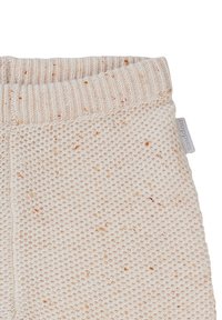 Lys beige strikkede bukser med et tekstureret vaffelmønster, ribbet talje og et lille mærke med brandnavn på siden.