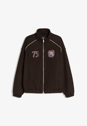 Dark brown zipped jacket with white piping, number "75" on left chest, and a crest with "Lost Legacy" text on right chest.