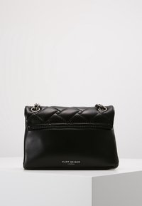 Svart läderhandväska med ett quiltat övre panel, silverdetaljer och en logotyp framtill. Kompakt rektangulär form som är lämplig för nödvändigheter.