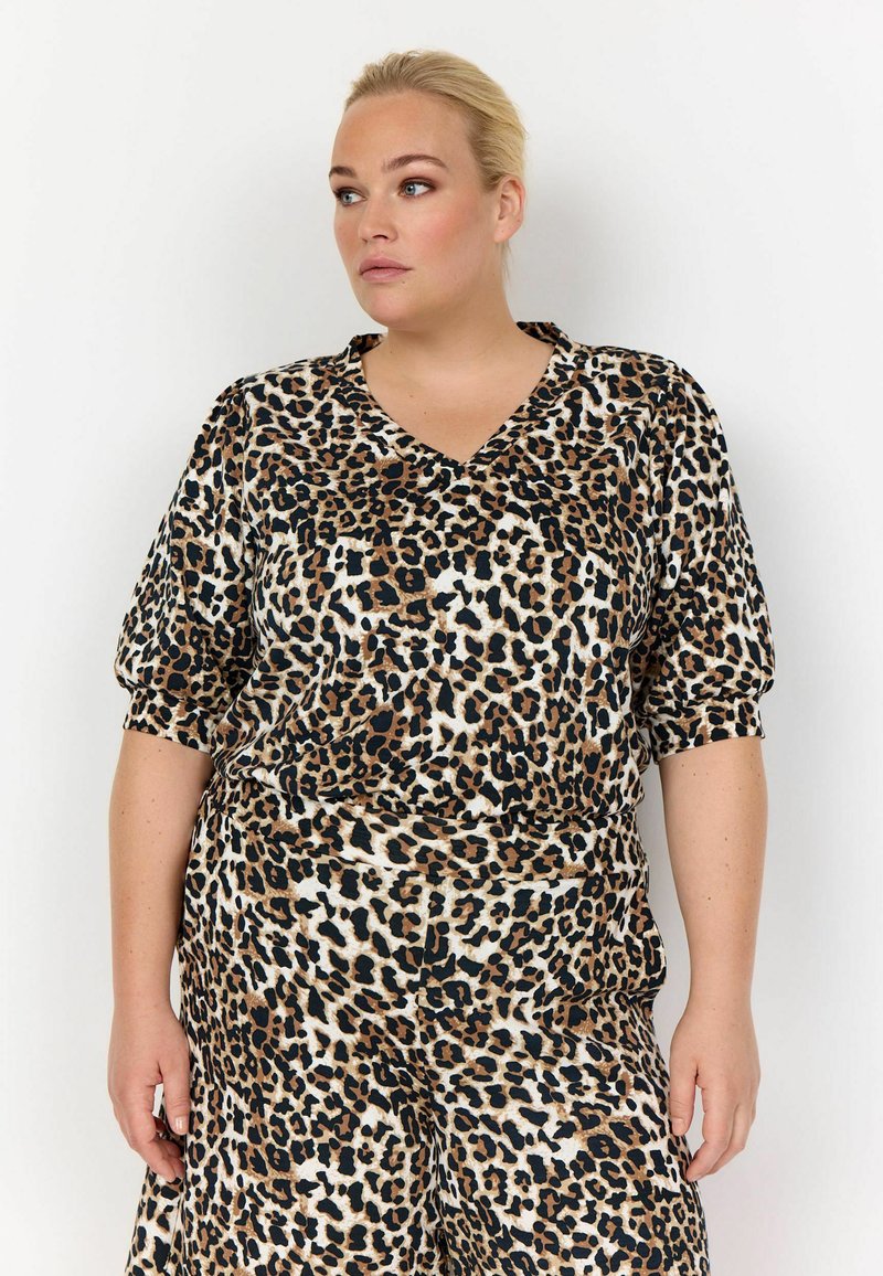 Bluse med leopardmønster, v-hals, korte puffærmer og afslappet pasform. Lavet af et blødt stof med brune og sorte mønsterdetaljer.