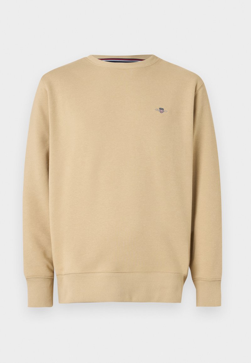 Sweat-shirt beige en tissu doux, avec un col rond, des manches longues et un petit logo brodé sur le côté gauche de la poitrine.