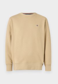 Sweat-shirt beige en tissu doux, avec un col rond, des manches longues et un petit logo brodé sur le côté gauche de la poitrine.