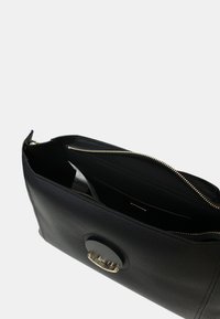 Sac en cuir noir avec une finition texturée, comprenant une fermeture éclair dorée et un accent métallique circulaire à l'avant. L'intérieur dispose de plusieurs compartiments.