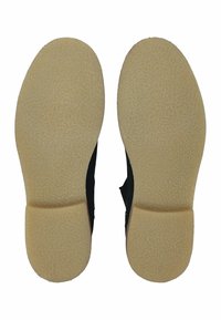 Chaussures noires avec une semelle en caoutchouc texturé, dotées d'un talon arrondi et d'une section intermédiaire, offrant une adhérence et une durabilité.