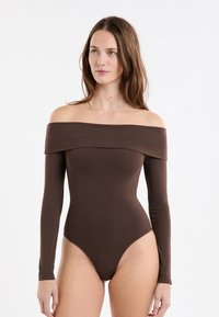 Brązowe body z opuszczanymi ramionami i długimi rękawami, wykonane z gładkiej tkaniny. Posiada wysokie wycięcie nogawek i dopasowany krój.