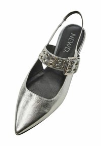 Srebrny metaliczny but na odkrytej pięcie z ostrym noskiem, skórzana cholewka o teksturowanej powierzchni oraz szeroki pasek z klamrą z okrągłymi wycięciami.