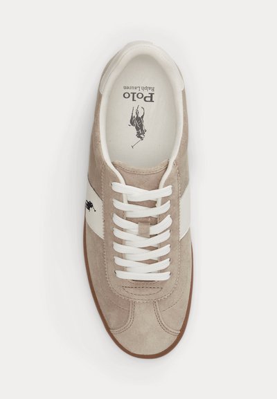 Μπεζ σουέντ αθλητικό παπούτσι με λευκές πλαϊνές επιφάνειες, λευκά κορδόνια, καφέ σόλα και λογότυπο Polo Ralph Lauren στην εσωτερική σόλα και στο πλάι.