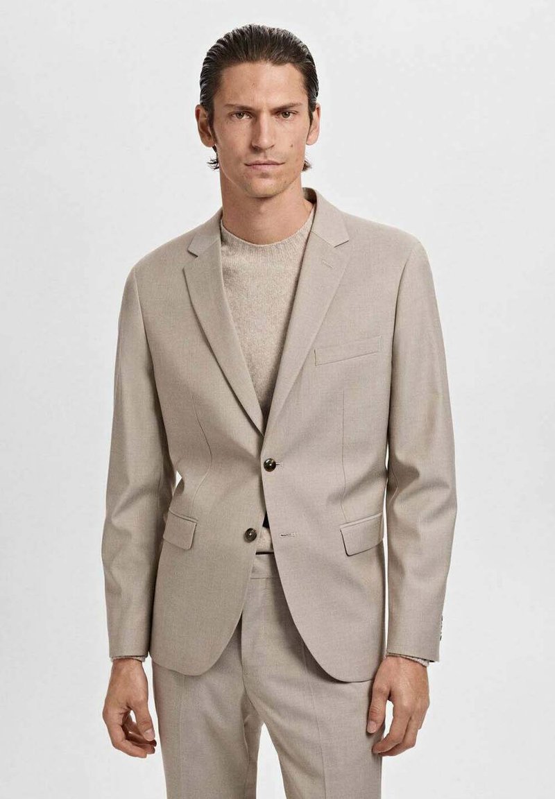 Beige tailored blazer with two front pockets, single button closure, and notch lapels, paired with a light beige knit sweater.