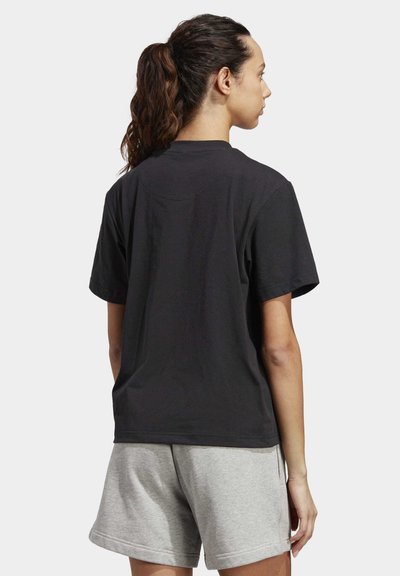 Mustape camiseta lühikeste varrukatega ümarate kaelustega, nähtud tagantpoolt, koos hallide spordilühikestega.