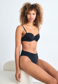 Black lingerie set featuring padded bra with adjustable straps and high-waisted briefs. Smooth fabric with minimal stitching details.