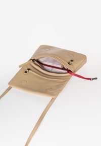 Borsa a tracolla in pelle beige con due scomparti con cerniera, design piatto, tracolla regolabile e tirazip rosso all'interno.
