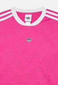 Svijetlo ružičasta Adidas majica s teksturiranim uzorkom lista, bijelim ovratnikom i tri bijele pruge na svakom ramenu. Središnji logo na prsima.