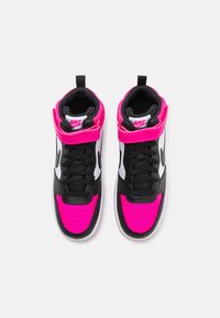 Vysoké tenisky Nike s čierno-bielym dizajnom a jasne ružovými akcentmi. Hladký materiál s perforovanou špičkou a suchým zipsom.