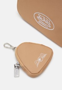 Beige nylon myntficka med en rundad triangelform, vit vingad logodetalj, silvrig dragkedja och metallklämma för fäste.